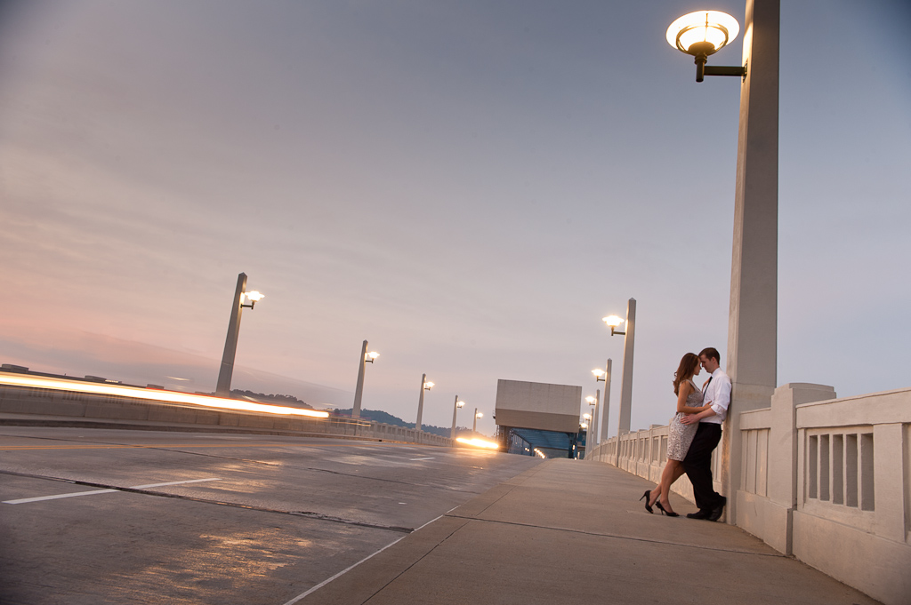 An engaged couple embrace at twilight on the Market Street bridge in Chattanooga, TN.